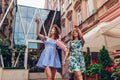 Outdoor portrait of two young beautiful women walking on city street. Best friends hanging, having fun