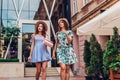 Outdoor portrait of two young beautiful women walking on city street. Best friends hanging, having fun