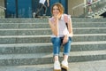 Outdoor portrait of 14 year old schoolgirl. Young girl with backpack, sits on the steps holds school notebook in her hands. Royalty Free Stock Photo