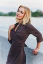 Outdoor portrait of young beautiful caucasuan woman with long straight hair in short black dress, beige shoes holding Royalty Free Stock Photo