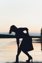 Outdoor portrait of young beautiful caucasuan woman with long straight hair in short black dress, beige shoes holding Royalty Free Stock Photo