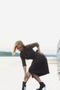 Outdoor portrait of young beautiful caucasuan woman with long straight hair in short black dress, beige shoes holding Royalty Free Stock Photo