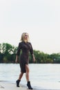 Outdoor portrait of young beautiful caucasuan woman with long straight hair in short black dress, beige shoes holding Royalty Free Stock Photo