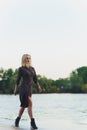 Outdoor portrait of young beautiful caucasuan woman with long straight hair in short black dress, beige shoes holding Royalty Free Stock Photo