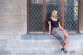 Outdoor portrait of a young beautiful fashionable happy lady posing on a street of the old city. Model wearing stylish Royalty Free Stock Photo