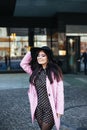 Outdoor portrait of a young beautiful fashionable woman walking on the street. Model wearing stylish pink coat, black Royalty Free Stock Photo