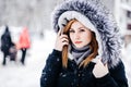 Outdoor portrait of young beautiful girl wearing in black jacket with a hood . Model posing in street. Winter holidays concept Royalty Free Stock Photo