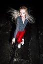 Outdoor portrait of young beautiful happy blond european lady posing on street at night. Model wearing stylish clothes red pants a Royalty Free Stock Photo