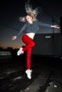 Outdoor portrait of young beautiful happy blond european lady posing on street at night. Model wearing stylish clothes red pants a Royalty Free Stock Photo
