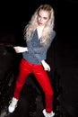 Outdoor portrait of young beautiful happy blond european lady posing on street at night. Model wearing stylish clothes red pants a Royalty Free Stock Photo