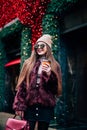 Outdoor portrait of young beautiful happy smiling girl posing on street. Model wearing stylish warm clothes.Keeps coffee. concept Royalty Free Stock Photo