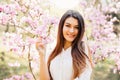 Outdoor portrait of a young beautiful woman near magnolia tree with flowers. Royalty Free Stock Photo