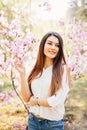 Outdoor portrait of a young beautiful woman near magnolia tree with flowers. Royalty Free Stock Photo