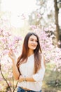 Outdoor portrait of a young beautiful woman near magnolia tree with flowers. Royalty Free Stock Photo