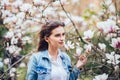 Portrait of a young beautiful woman near magnolia tree with flowers. Royalty Free Stock Photo