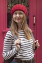 Outdoor portrait of young beautiful woman in striped shirt and red beret. A lady is dressed in the French style. Royalty Free Stock Photo