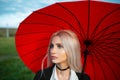 Outdoor portrait of young blonde beautiful girl, holding red umbrella. Royalty Free Stock Photo