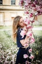 Outdoor portrait of young blonde woman posing with magnolia tree in bloom Royalty Free Stock Photo