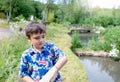 Outdoor portrait young boy standing next to pond feeding the duck. Child having fun the day trip at the natural park, Kid relaxing Royalty Free Stock Photo