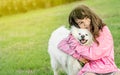 outdoor portrait of young caucasian girl with her pet dog, child owner with white fluffy japanese spitz puppy Royalty Free Stock Photo