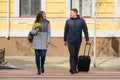 Outdoor portrait of young couple walking with suitcase on city street, happy young man and woman travel in spring, people on zebra