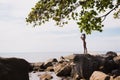 Outdoor portrait of young elegant fit woman standing on a rock near tropical beach with sea. Sports girl in bikini enjoy Royalty Free Stock Photo