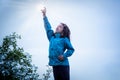 Outdoor portrait of young girl in blue jacket reaching her arm in the air to catch the sun. Royalty Free Stock Photo