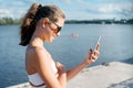 Outdoor portrait of young girl of 13, 14 years old with mobile phone, on summer day near the river Royalty Free Stock Photo