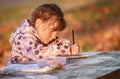 Outdoor portrait of young happy child girl drawing or writing in