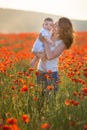 Outdoor portrait. Young mother and her daughter enjoy life time together on a poppy field . Concept of love and happy family. Royalty Free Stock Photo