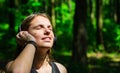 Portrait of young teenager brunette girl with long hair. Happy young woman listening to music with headphones in forest. Royalty Free Stock Photo