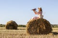 Outdoor portrait of young woman in a pink dress sitting on hay bale Royalty Free Stock Photo