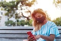 Outdoor portrait of a young woman with a protective mask and cell phone. Girl with a cell phone sitting in the park Royalty Free Stock Photo