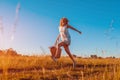 Outdoor portrait of young woman with red curly hair jumping with a bag of flowers. Happy summer holidays Royalty Free Stock Photo