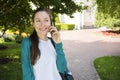An outdoor portrait of young woman talking on the phone in a city park on a sunny day. A happy girl is calling over a phone line Royalty Free Stock Photo