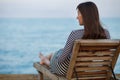 Outdoor portrit of beautiful young woman relaxing at the seacoast at the evening