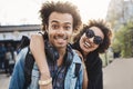 Outdoor protrait of african-american couple hugging and smiling broadly at camera while walking in park and expressing