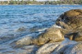 Outdoor reservoir wavy water surface rocky shore line scenic view with stones texture and fuzzy motion of drop splash foreground, Royalty Free Stock Photo