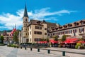 Outdoor restaurant, houses and catholic church belfry under blue sky in Annecy, France