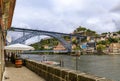 Outdoor restaurant terrace by Dom Luis I bridge in Ribeira and the Douro river with tourist boats in Porto, Portugal Royalty Free Stock Photo