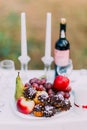 Outdoor romantic dinner table settings with wine, glasses, sweets and candles