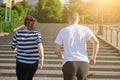 Outdoor running mature couple. Man and woman of 40 years old running upstairs, view from the back