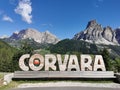 Outdoor scene of a wooden sign with the word "Corvara" in Italy