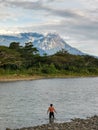 Outdoor scenery during day time with a river, forest, man and mount kinabalu as a background.