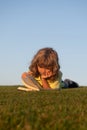 Outdoor school, motivation learning kids. Child boy is reading a book on the spring park. Relaxing on the grass in the Royalty Free Stock Photo