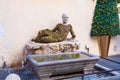 Outdoor sculpture of mossy overgrown man lying on the stone above the fountain in the front entrance of Canova Tadolini Museum in Royalty Free Stock Photo