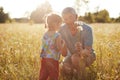 Outdoor shot of affectionate grandfather gives beautiful bouquet of camomiles to his small granddaughter, spends leisure time toge