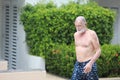 Outdoor shot attractive bearded senior caucasian male in swimming wear walking by swimming pool in hotel outdoor during rainy day Royalty Free Stock Photo