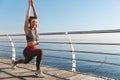 Outdoor shot of attractive young fitness woman stretching, warming-up before workout, doing exercises at the seaside Royalty Free Stock Photo