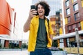 Outdoor shot of cheerful young man have a online meeting group conversation on mobile phone while walking in the street. Happy Royalty Free Stock Photo